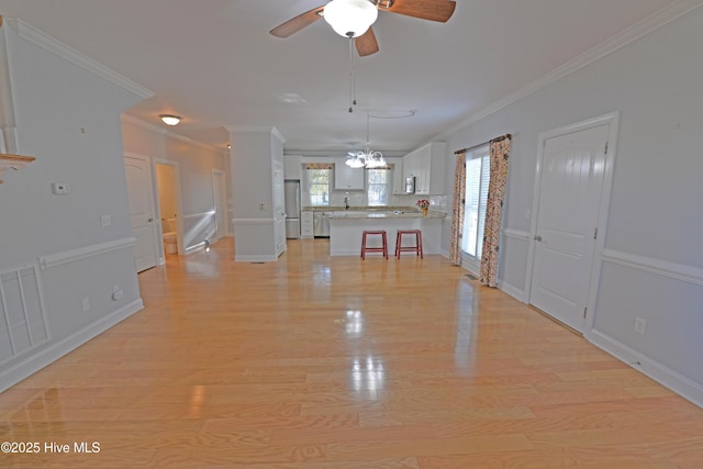 unfurnished living room with light wood finished floors, visible vents, ceiling fan with notable chandelier, and crown molding