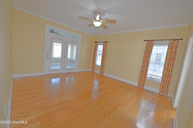 empty room with light wood-type flooring, a ceiling fan, visible vents, and crown molding