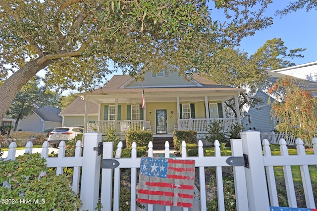 view of front of property with a gate, covered porch, a fenced front yard, and roof with shingles