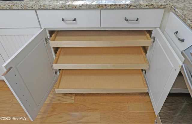 interior details with light stone counters, open shelves, and white cabinetry