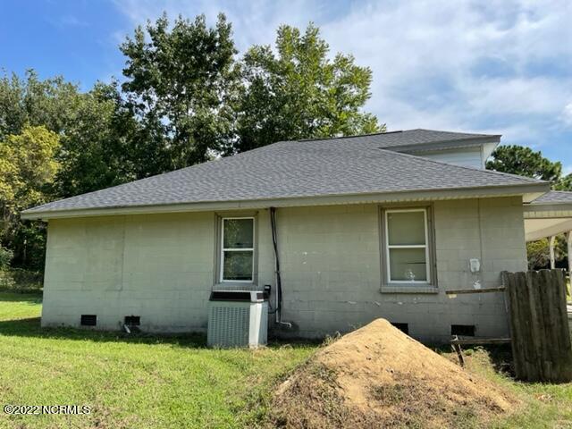 rear view of property with central AC and a lawn