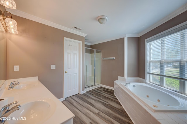 bathroom featuring wood finished floors, a jetted tub, a shower stall, double vanity, and crown molding