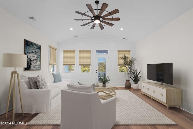 living room featuring visible vents, lofted ceiling, a ceiling fan, and wood finished floors