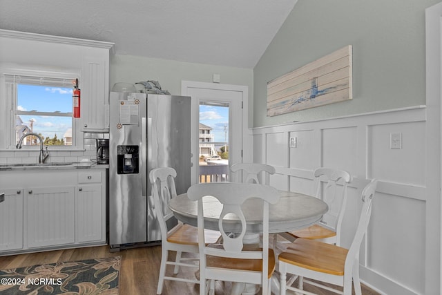 dining room with dark wood-type flooring, lofted ceiling, and sink