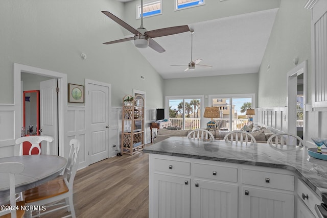 kitchen featuring light hardwood / wood-style flooring, white cabinets, high vaulted ceiling, and dark stone counters