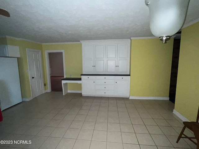 interior space featuring light tile floors, a textured ceiling, and crown molding
