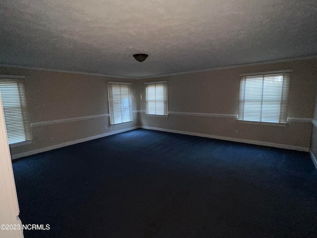 spare room featuring dark carpet, a textured ceiling, and crown molding