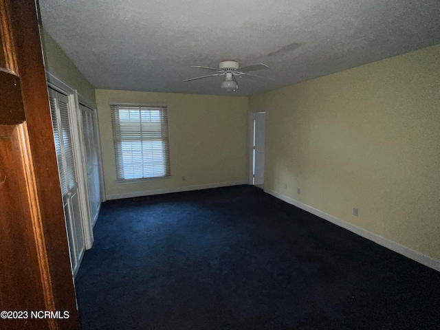 carpeted spare room featuring ceiling fan and a textured ceiling