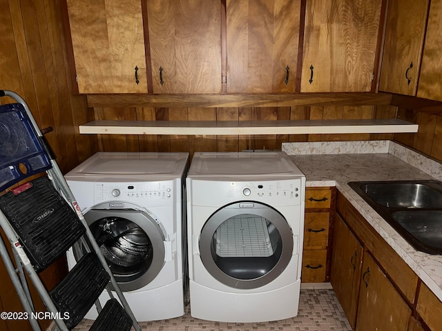 laundry area with washer and dryer, wooden walls, cabinets, and sink