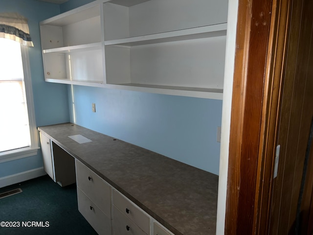 unfurnished office with built in desk and dark carpet