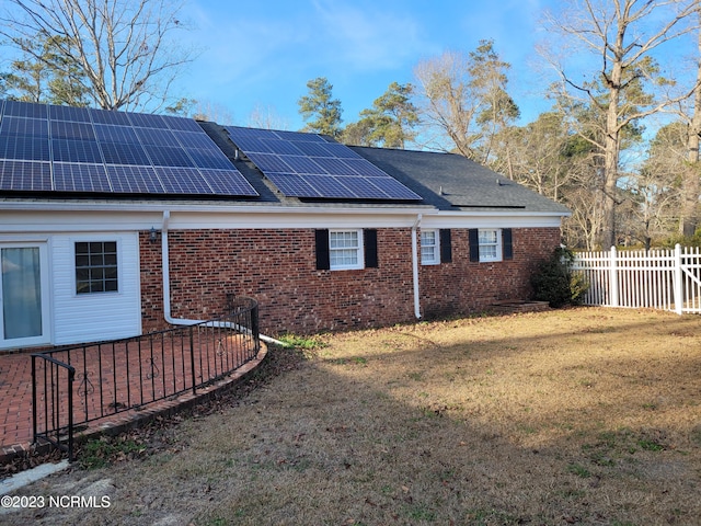 view of side of home with a lawn and solar panels