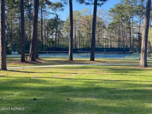 view of property's community with tennis court and a lawn