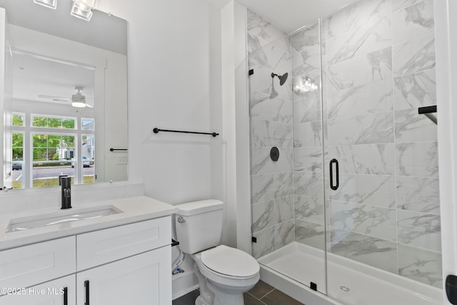 bathroom with an enclosed shower, vanity, toilet, and ceiling fan