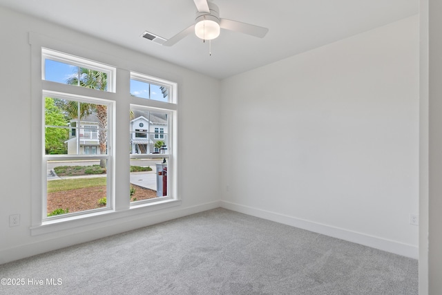 carpeted spare room featuring ceiling fan and plenty of natural light