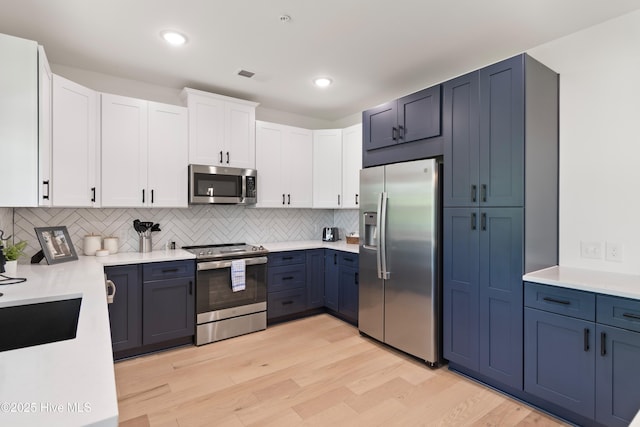 kitchen featuring white cabinetry, appliances with stainless steel finishes, backsplash, and light wood-type flooring