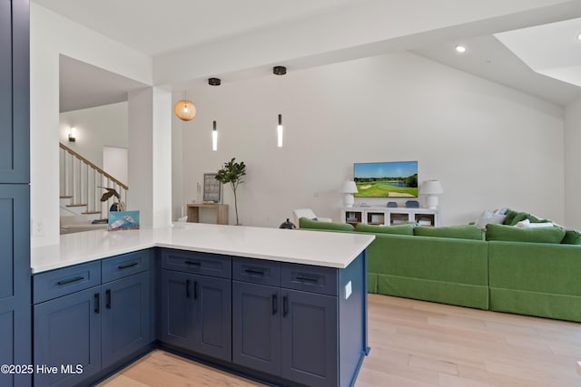 kitchen featuring hanging light fixtures, lofted ceiling, light hardwood / wood-style floors, and kitchen peninsula