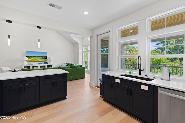 kitchen with sink, hanging light fixtures, light wood-type flooring, dishwasher, and a healthy amount of sunlight