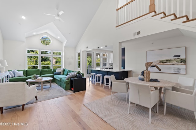 living room featuring ceiling fan, high vaulted ceiling, and light hardwood / wood-style flooring