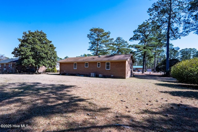 rear view of property featuring brick siding, crawl space, and central air condition unit