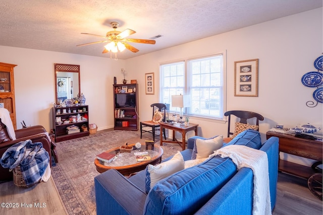 living area with visible vents, a textured ceiling, and wood finished floors