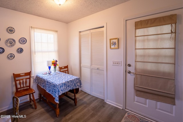 dining space featuring a textured ceiling, dark wood-type flooring, and baseboards