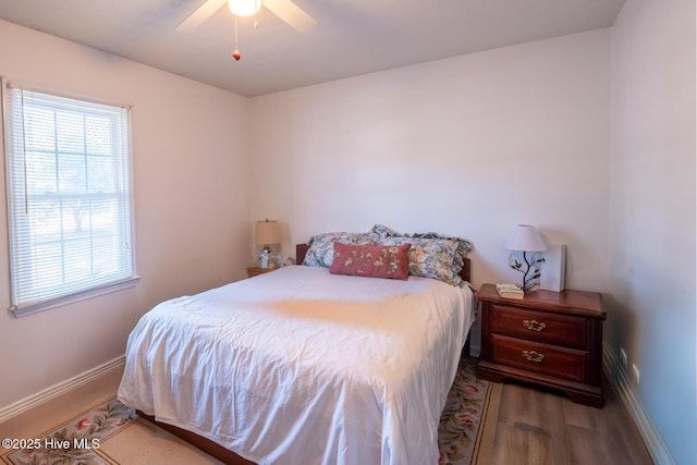 bedroom featuring a ceiling fan, baseboards, multiple windows, and light wood finished floors