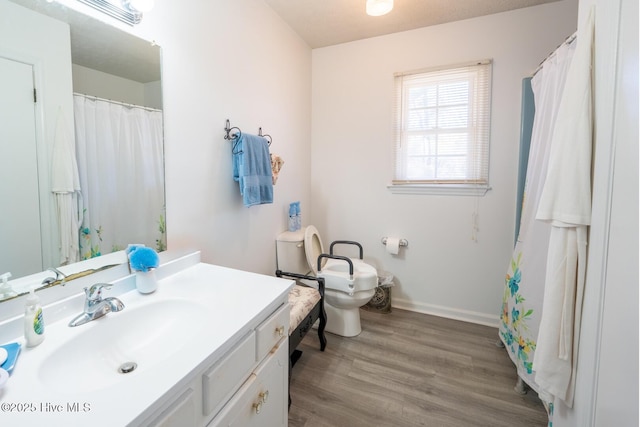 bathroom featuring toilet, baseboards, wood finished floors, and vanity