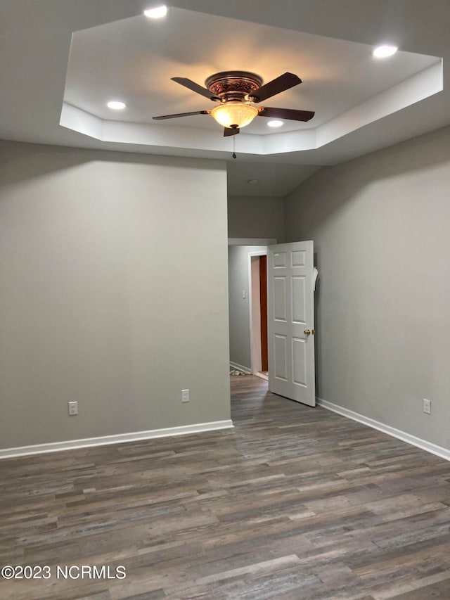 unfurnished room featuring ceiling fan, a raised ceiling, and hardwood / wood-style floors