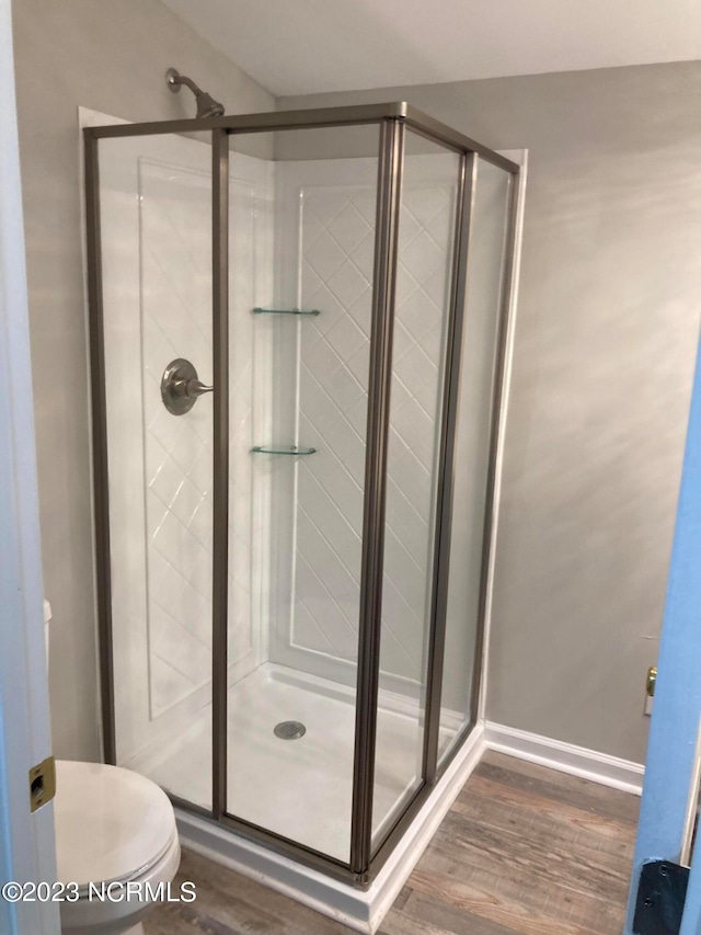 bathroom featuring a shower with door, hardwood / wood-style floors, and toilet