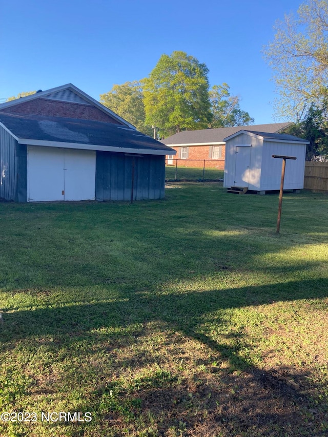 view of yard with a storage shed, an outbuilding, and fence