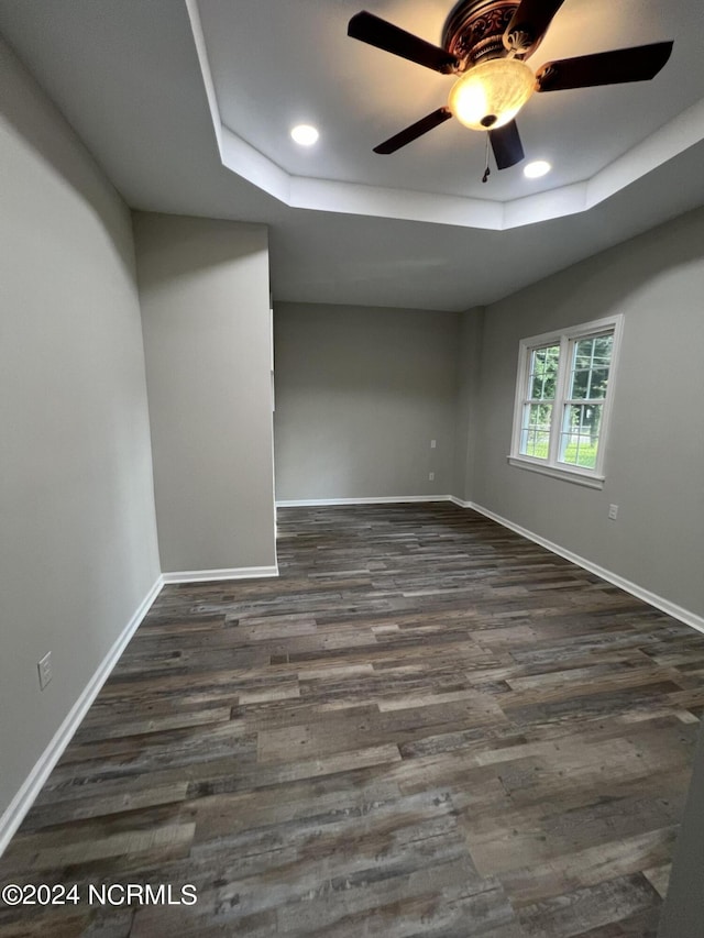 spare room with baseboards, a raised ceiling, a ceiling fan, dark wood-style floors, and recessed lighting