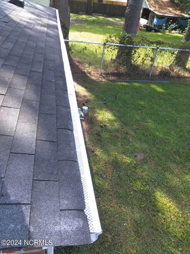 exterior details with a shingled roof and fence