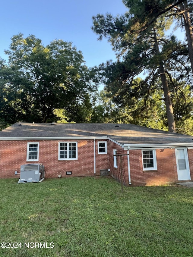 rear view of property featuring brick siding, a yard, and central AC unit