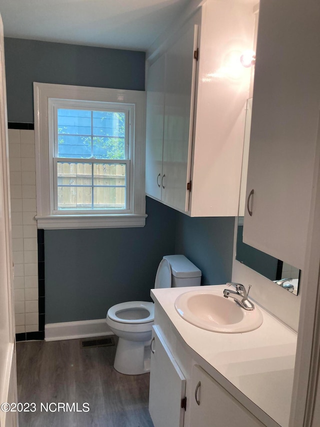 bathroom featuring toilet, wood finished floors, vanity, visible vents, and baseboards