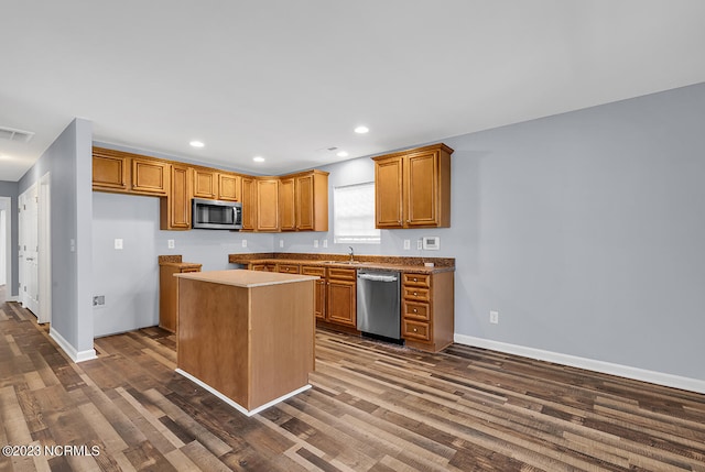 kitchen with dark wood-type flooring, appliances with stainless steel finishes, a center island, and sink