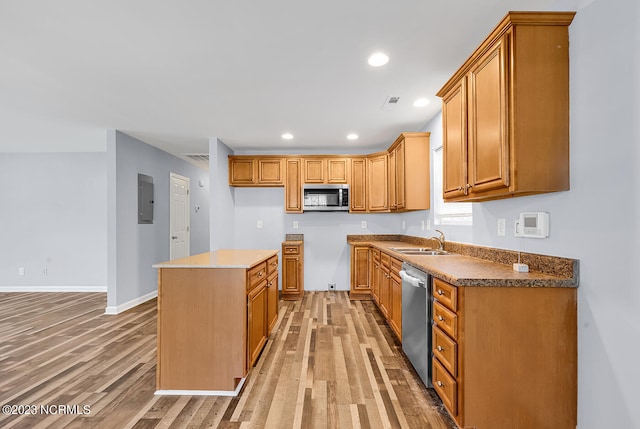 kitchen featuring wood-type flooring, a kitchen island, appliances with stainless steel finishes, and sink