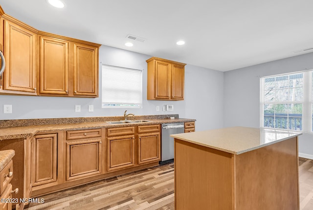 kitchen with sink, light hardwood / wood-style flooring, stainless steel dishwasher, light stone countertops, and a center island