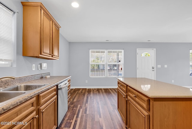 kitchen with a center island, dishwasher, dark hardwood / wood-style flooring, sink, and light stone countertops