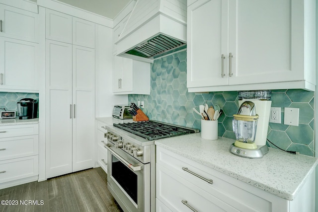 kitchen with light hardwood / wood-style flooring, white cabinetry, premium range hood, and high end stove