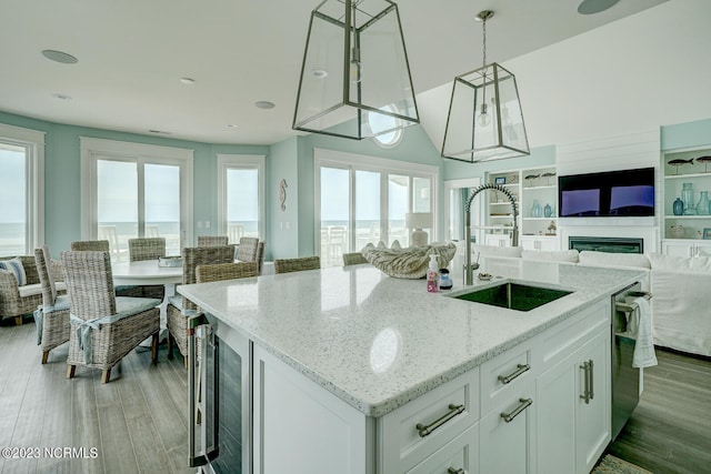 kitchen featuring hanging light fixtures, light wood-type flooring, white cabinets, and sink