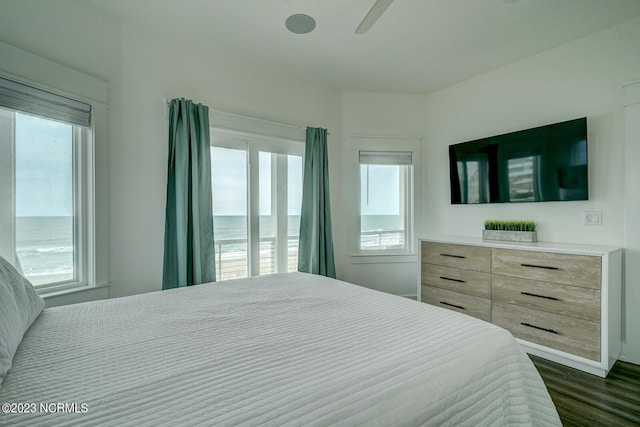 bedroom featuring a water view, multiple windows, ceiling fan, and dark hardwood / wood-style floors