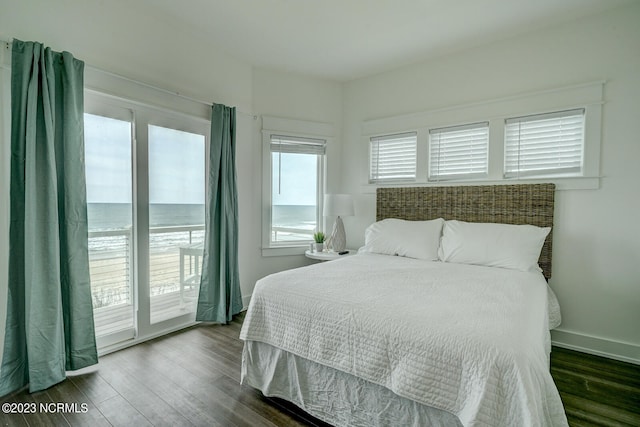 bedroom with dark hardwood / wood-style floors, access to exterior, and a water view