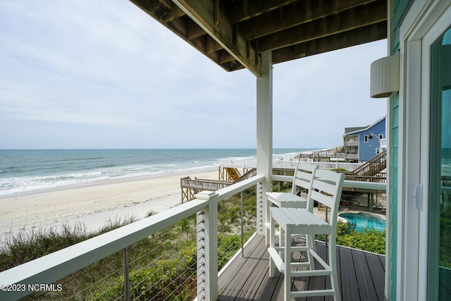 balcony with a water view and a view of the beach