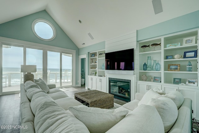 living room with high vaulted ceiling, a water view, and light hardwood / wood-style flooring