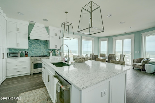 kitchen with stainless steel appliances, a center island with sink, sink, custom range hood, and dark hardwood / wood-style flooring