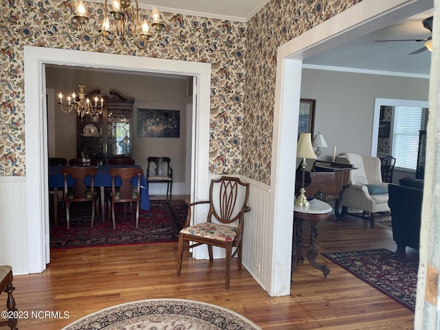 interior space with wood-type flooring, ceiling fan with notable chandelier, and ornamental molding