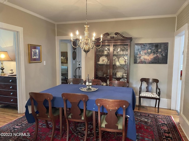 dining space with crown molding, a notable chandelier, and hardwood / wood-style flooring