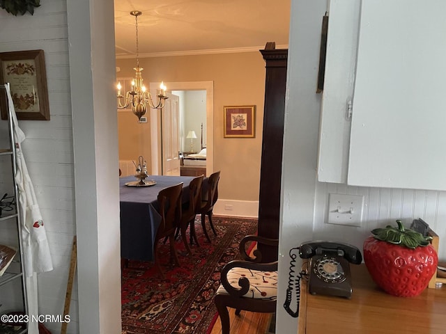 dining space with a notable chandelier, ornamental molding, and hardwood / wood-style flooring