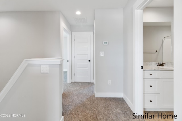 corridor with sink and light carpet