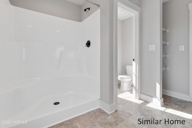 bathroom featuring tile flooring, a shower, and toilet